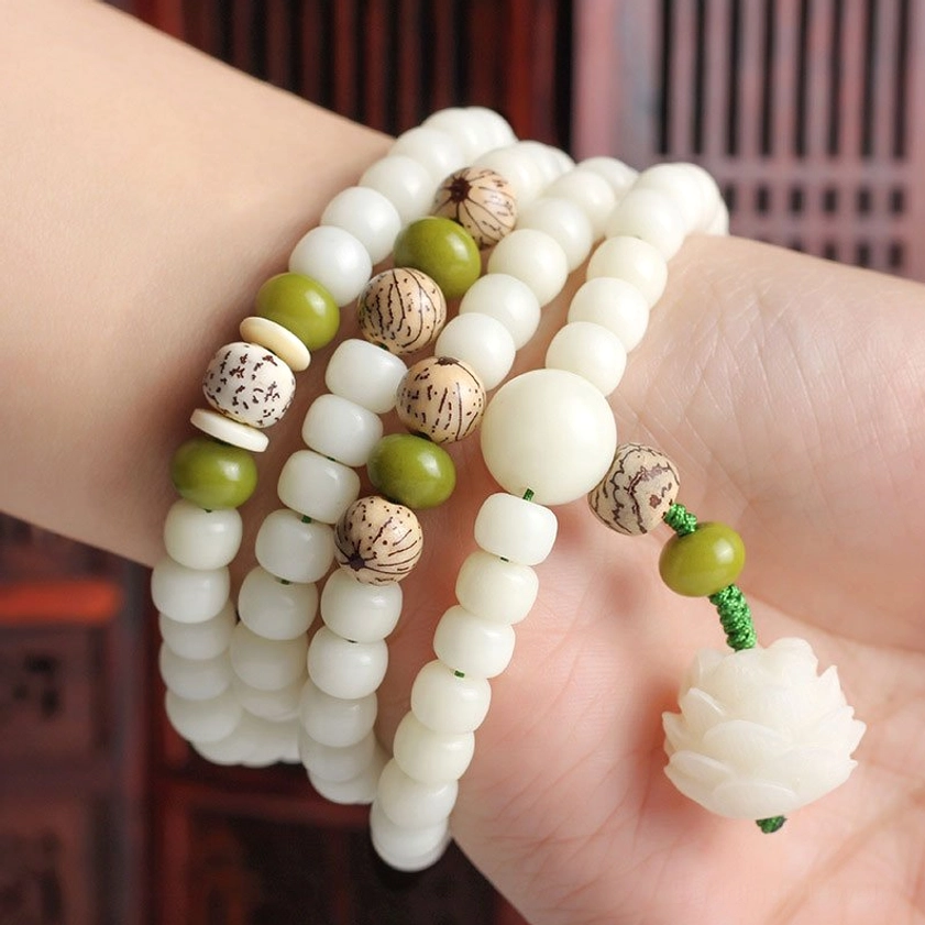 Wrist wearing white bodhi lotus mala bracelet with layered design and pendant accents