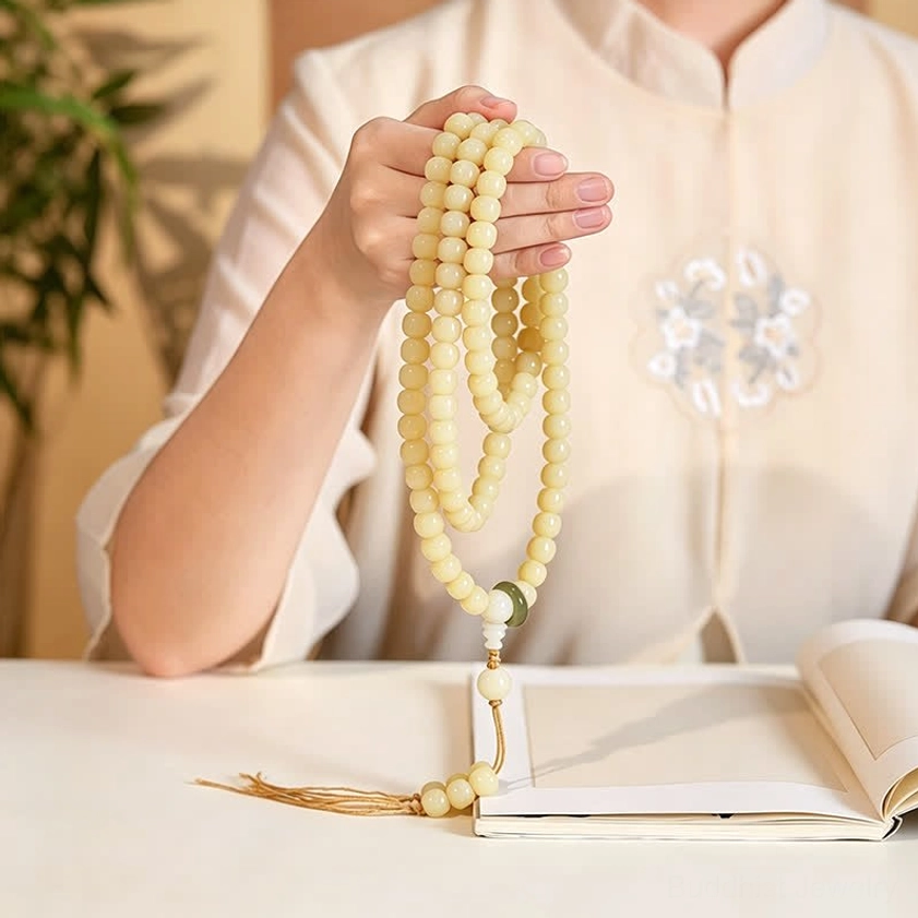 Folded bodhi seed mala beads showing polished texture and woven tassel, close-up hand detail shot