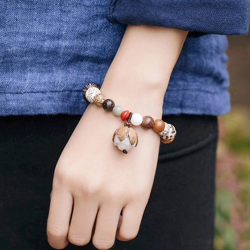 Bodhi mala bracelet with lotus pendant worn on wrist with dark clothing backdrop