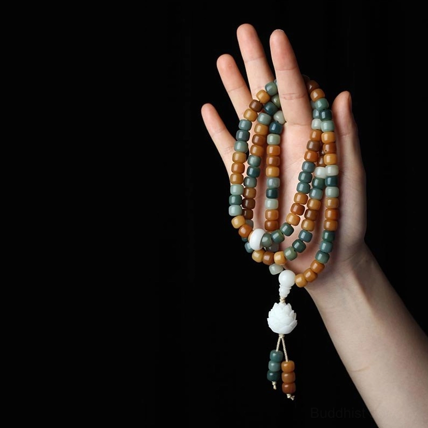 Multi-wrap bodhi bead bracelet worn on palm showing lotus pendant and earth-tone beads