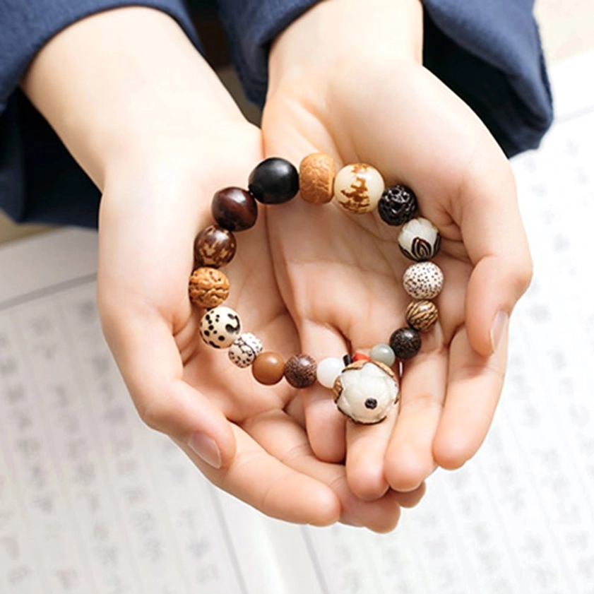 Multiple bodhi seed mala bracelets held in hands with Chinese script background