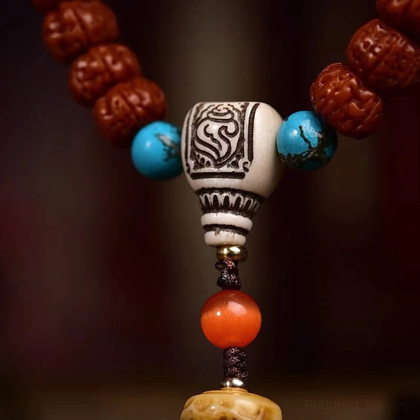 Detailed close-up of decorative guru connector bead with carved patterns in reddish brown, blue, white and orange tones