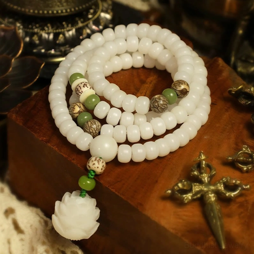 Multi-loop white bodhi bead mala necklace with accent green beads and lotus charm on wooden stand