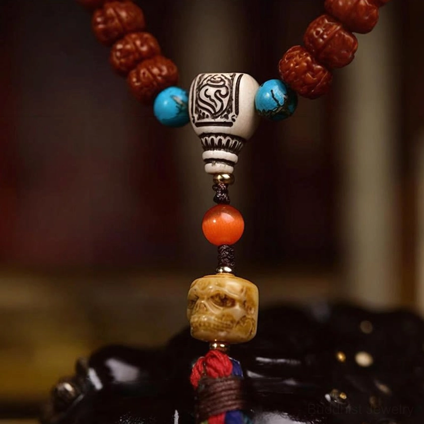 Closeup of bodhi seed mala pendant assembly showing carved bead with multicolor tassel fastener and ornamental detail