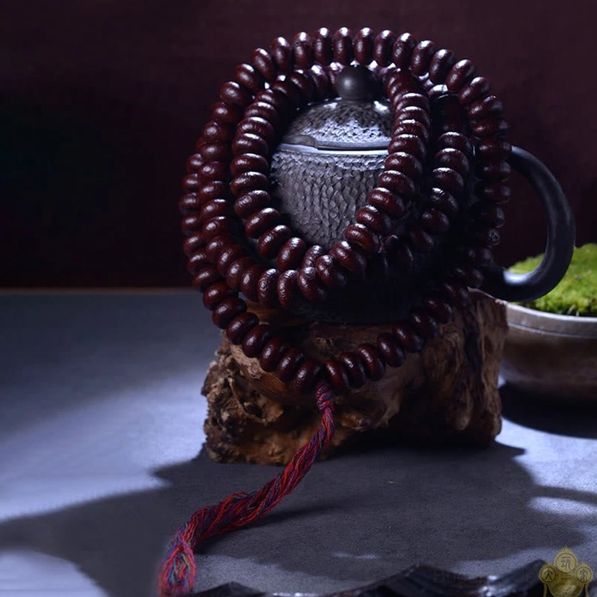 Purple Bodhi Seed 108 mala bracelet displayed on wooden teapot stand with red tassel