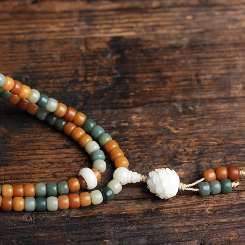 Bodhi meditation mala flat lay with two white lotus pendants and mixed earthy color beads