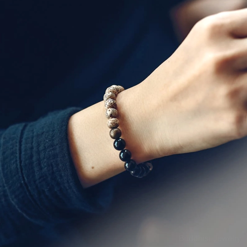 Woman wearing bodhi seed obsidian peace bracelet on wrist close-up side view