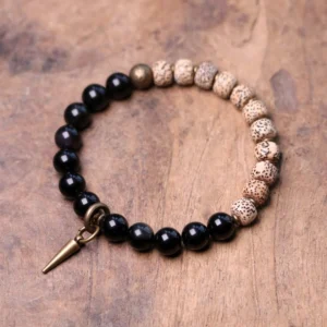 Bodhi seed and black obsidian Buddhist peace bracelet with brass accent on wooden table flat lay