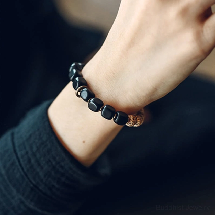 Peace bracelet with brass spike charm bodhi seeds and black obsidian on woman's wrist