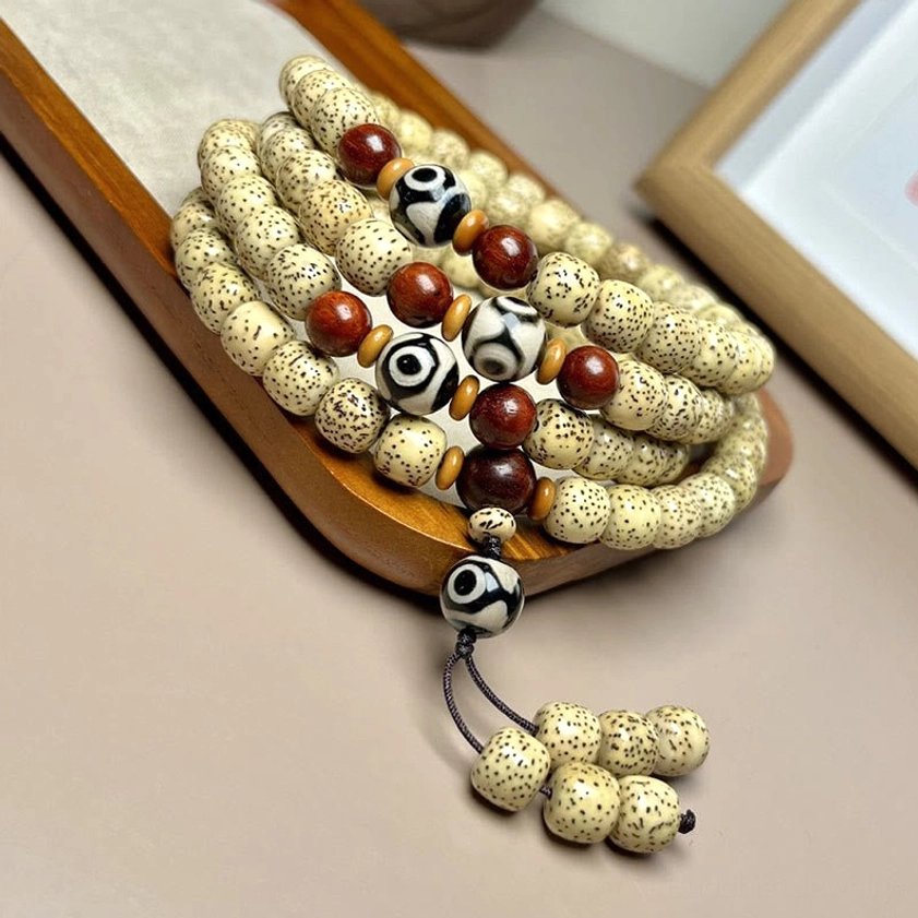 108 Bodhi mala beads close-up angled view highlighting spotted beads, red and brown spacers with detailed hand-painted Dzi bead