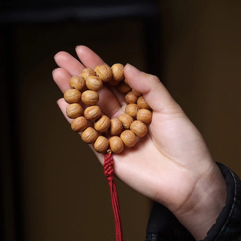 Close-up palm shot of authentic Phoenix Eye Bodhi prayer mala showing natural bead surface and craftsmanship