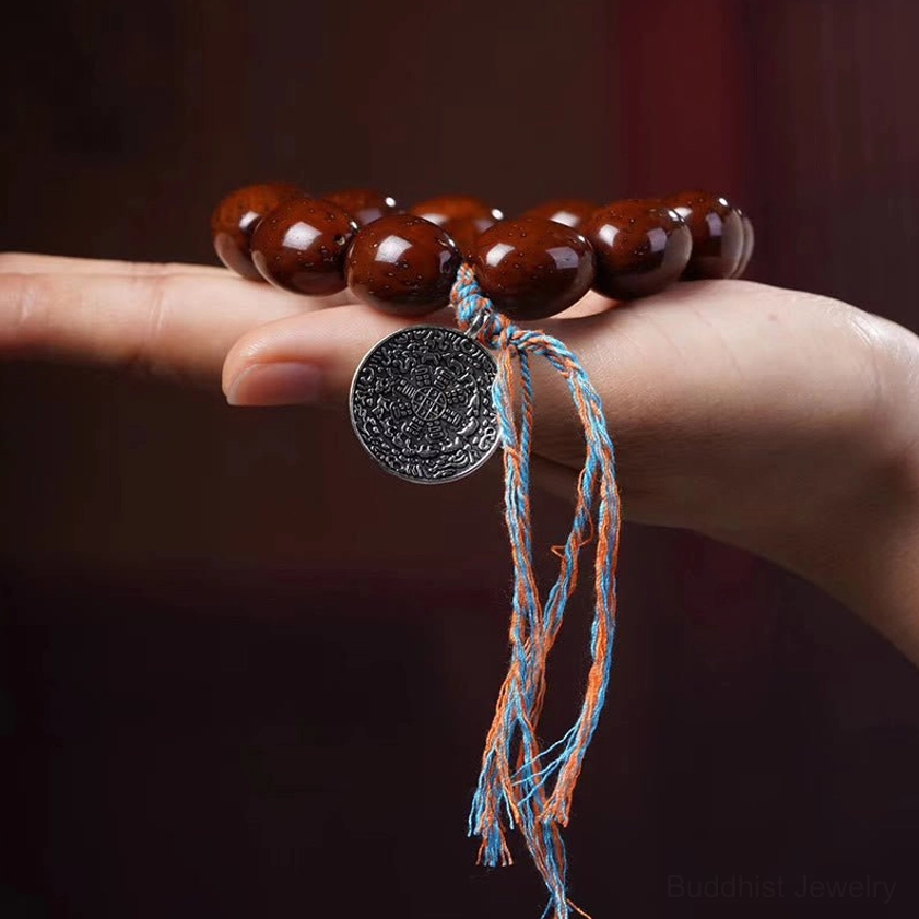 Purple gold rat bodhi prayer bracelet rested on finger showing bead detail and OM charm