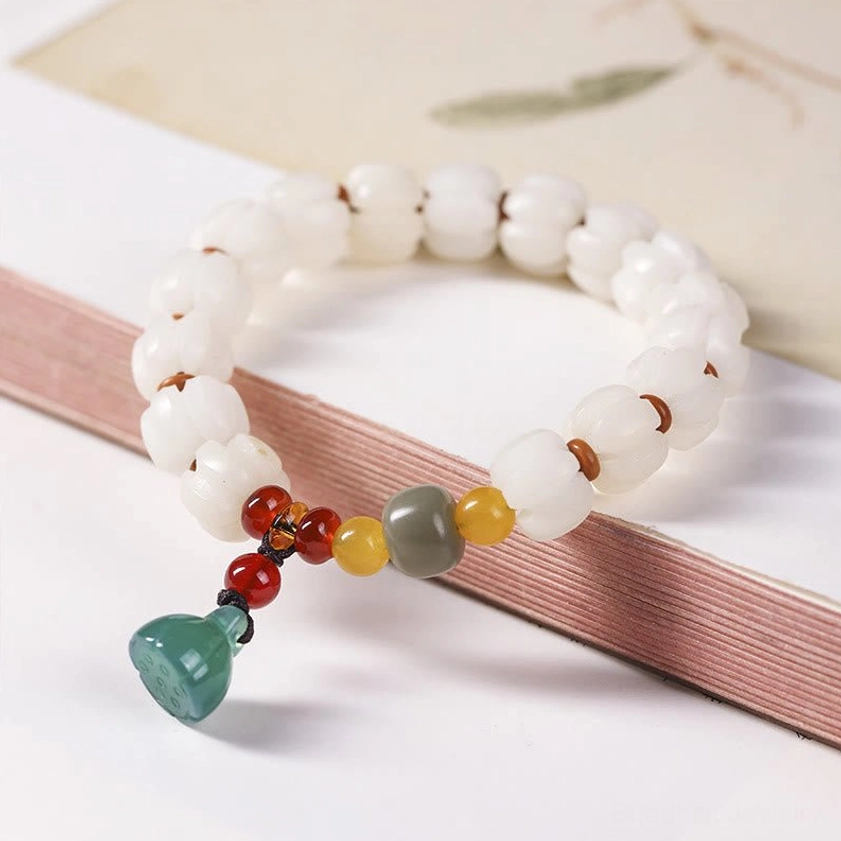 Buddhist bodhi seed bracelet with lotus charm displayed on stationery background showing bead details