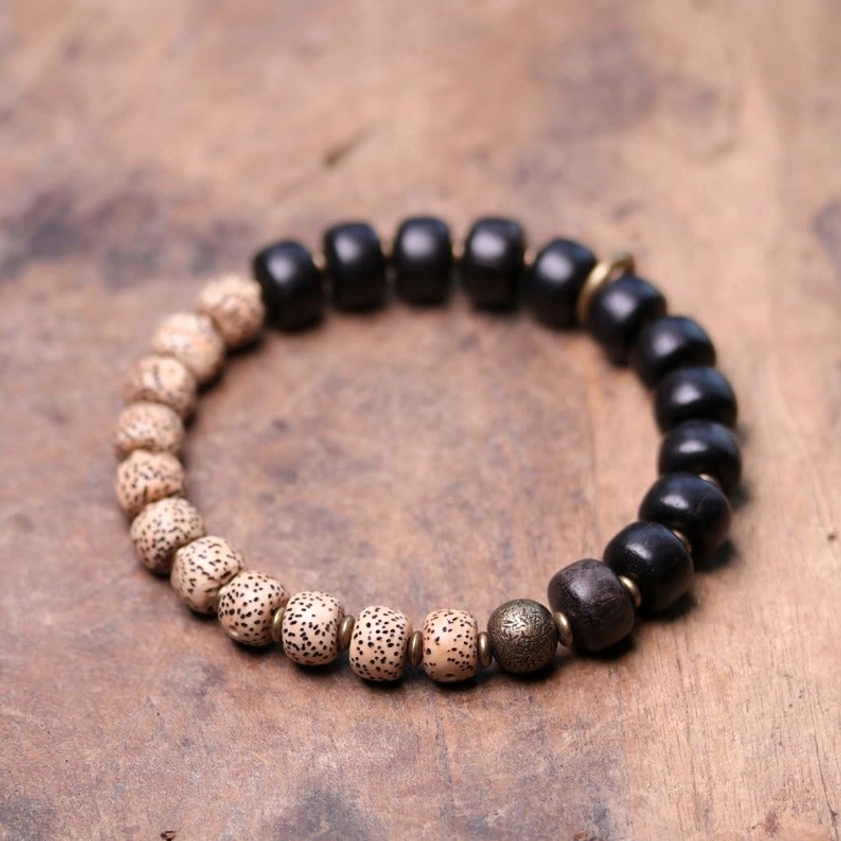 Dual-tone Buddhist bracelet round ebony wood bodhi seeds and brass accents on wooden table