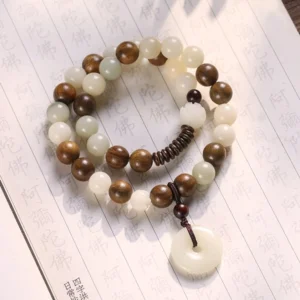 Bodhi seed and green sandalwood double wrap meditation bracelet with white peace buckle charm on Buddhist scripture background, handmade zen jewelry