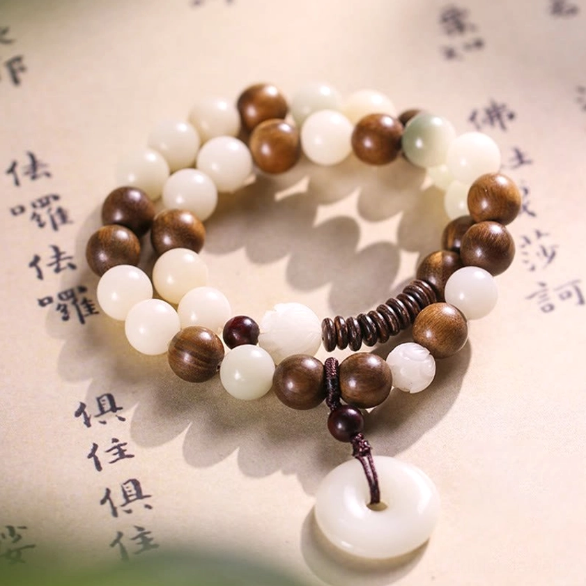 Handmade bodhi seed and sandalwood double wrap bracelet with peace buckle pendant, mixed bead tones on Buddhist background