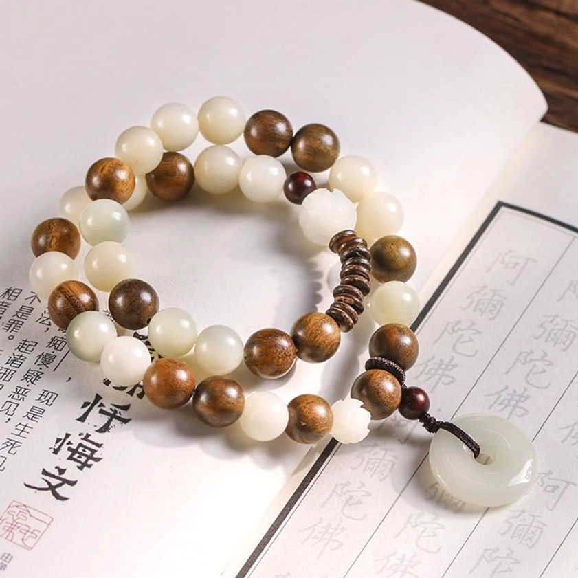 Spiritual double wrap bracelet with mixed brown and cream beads, peace buckle pendant displayed on Buddhist paper, handcrafted design
