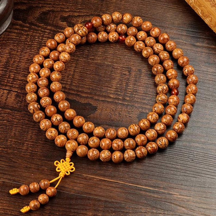 Complete bodhi seed 108-bead mala necklace top-down flat lay displaying full strand with yellow knot tassel and natural seed texture