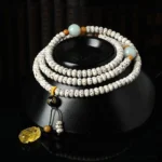 Bodhi seed mala bracelet with amber agate pendant displayed on black ceramic stand, showing side and top-down view