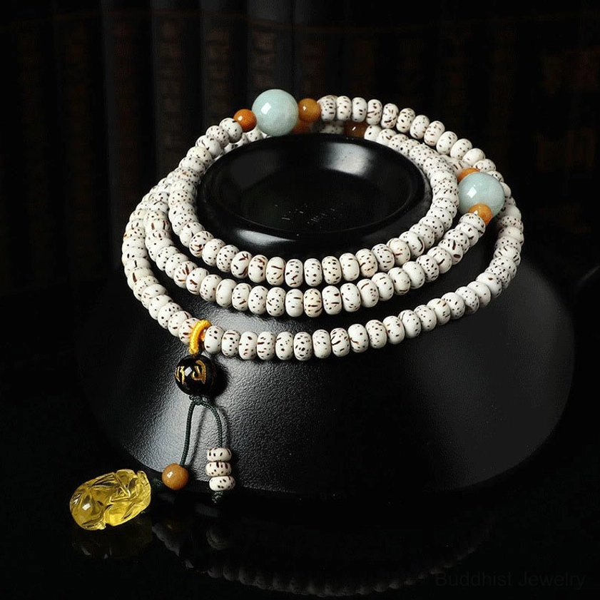 Bodhi seed mala bracelet with amber agate pendant displayed on black ceramic stand, showing side and top-down view