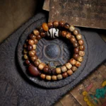 Bodhi seed amber dzi bead agate triple wrap Buddhist bracelet in top-down view showcasing the multi-loop design and material composition