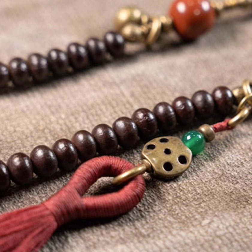Macro detail shot of purple bodhi mala beads showing smooth texture, brass metal charms, and colorful gemstone accents