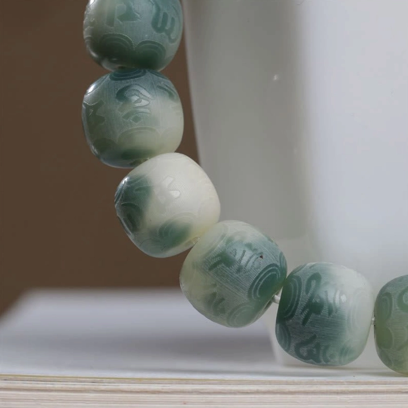 Detailed overhead close-up of carved Bodhi seed beads with sacred mantra engravings and gradient texture
