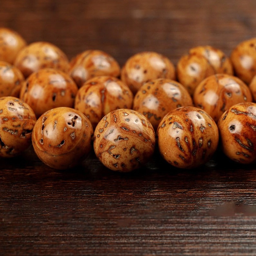 Close-up of individual bodhi seed beads showing round spotted brown surfaces natural drilled holes and detailed grain texture macro photography