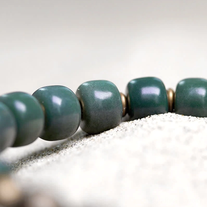 Macro close-up of cyan bodhi seed beads showing barrel shape with small bronze metal spacer details
