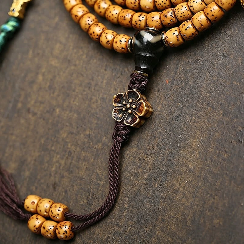 Detailed side view of Bodhi Seed prayer mala beads showing spotted texture with black spacer bead and four-leaf flower guru knot