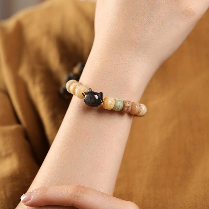 Bodhi seed and obsidian cat bracelet worn on wrist close-up, showing multicolor beads and protective black cat head charm