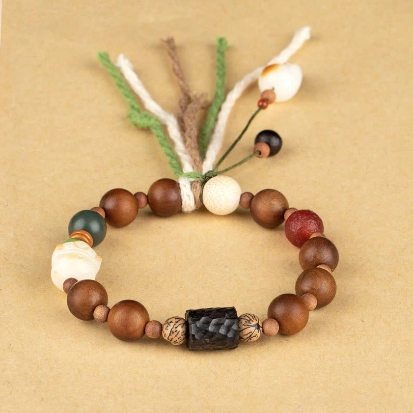 Flat lay overhead of wooden beaded protection bracelet with multi-strand cotton tassel and sandalwood beads on yellow background