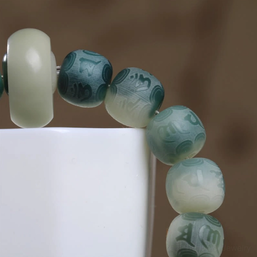 Close-up side view of engraved Bodhi seed beads showing mantra texture and smooth jade spacer ring
