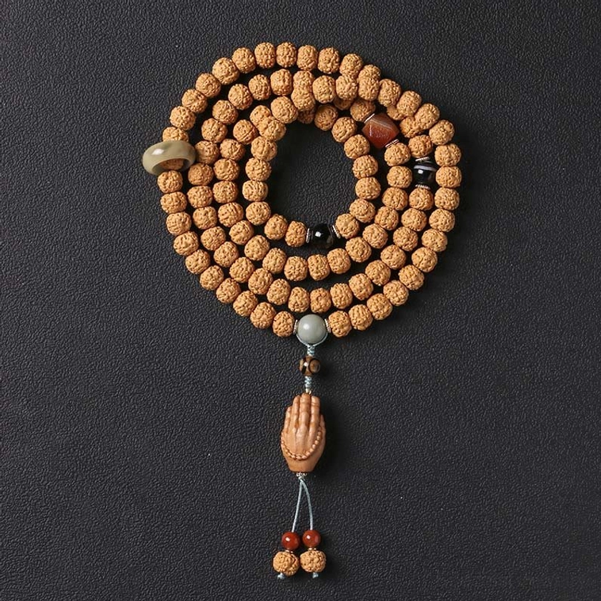 Neatly coiled bodhi seed Buddhist bracelet with metal spacers, stone accents, and Buddha hand tassel on dark studio background