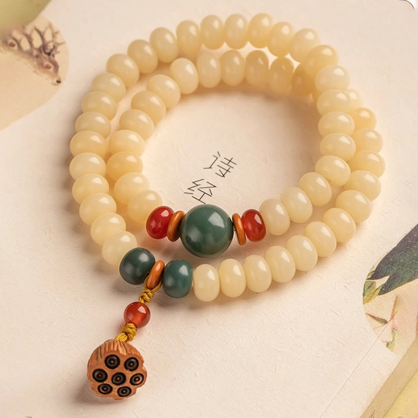 Complete Bodhi seed double wrap bracelet with lotus pendant laid on Chinese text book