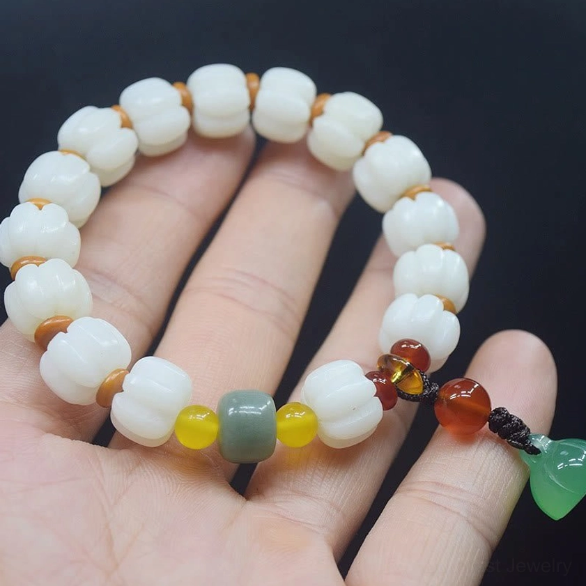 Handmade bodhi seed red agate bracelet held in palm showing lotus pendant and multicolor beads