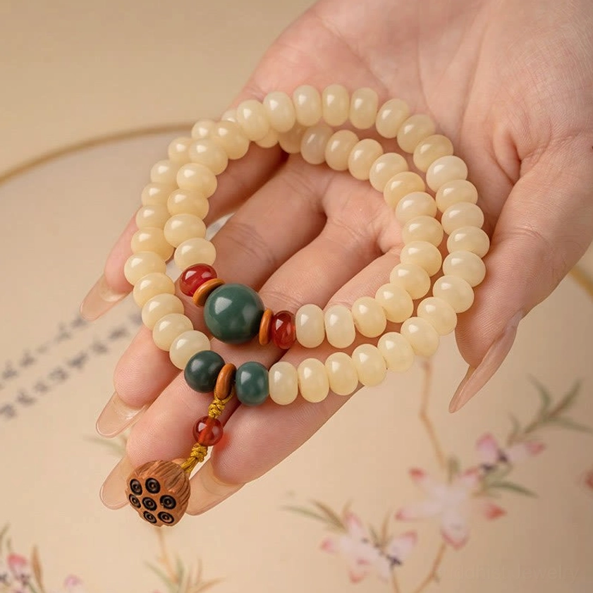 Hand-held Bodhi seed Buddhist bracelet featuring smooth matte off-white beads against floral background