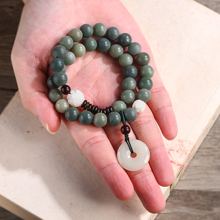 Cyan bodhi seed bracelet held in palm of hand showing 10mm beads, white jade peace buckle, and lotus bead details overhead perspective