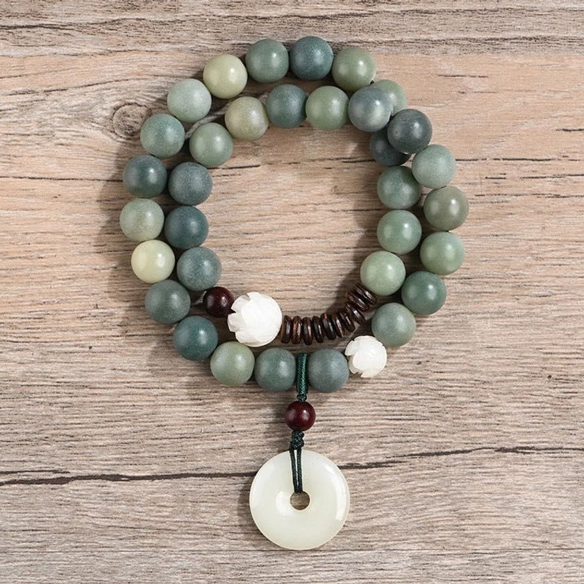 Green bodhi seed double wrap bracelet with white jade peace buckle charm on wooden table, top-down view of beaded bracelet design