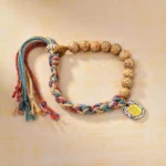 Multicolor bodhi seed Buddhist string bracelet with wealth goddess charm, featuring vibrant woven rope and spotty beads on beige background