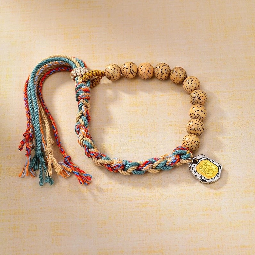 Multicolor bodhi seed Buddhist string bracelet with wealth goddess charm, featuring vibrant woven rope and spotty beads on beige background
