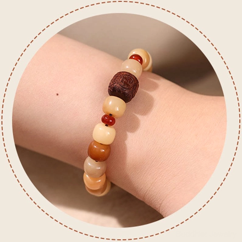 Bodhi seed bracelet worn on wrist close-up side view showing earthy tone barrel beads with wooden carved focal bead against studio background