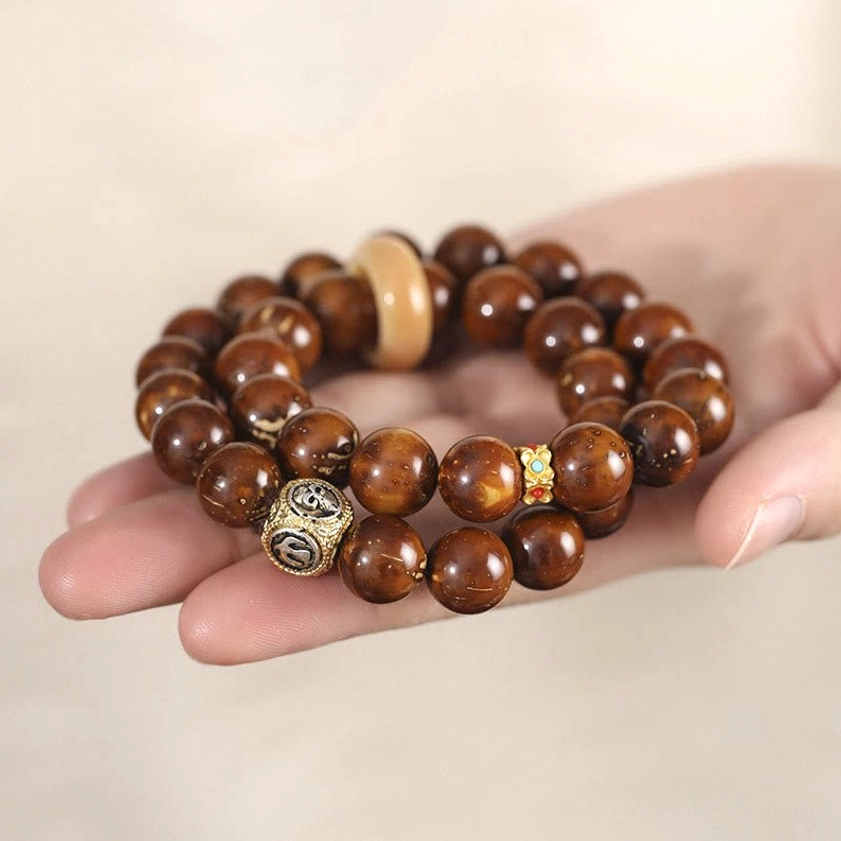 Close-up palm view of purple gold rat bodhi seed bracelet showing reddish-brown beads with metal and ring spacer