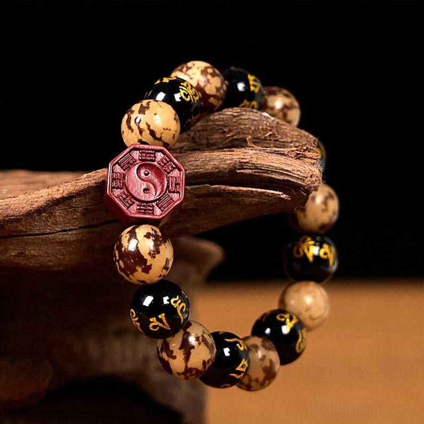 Buddhist prayer bracelet side profile showing spotted Bodhi beads, mantra engravings, and red cinnabar Bagua focal bead on wooden bark