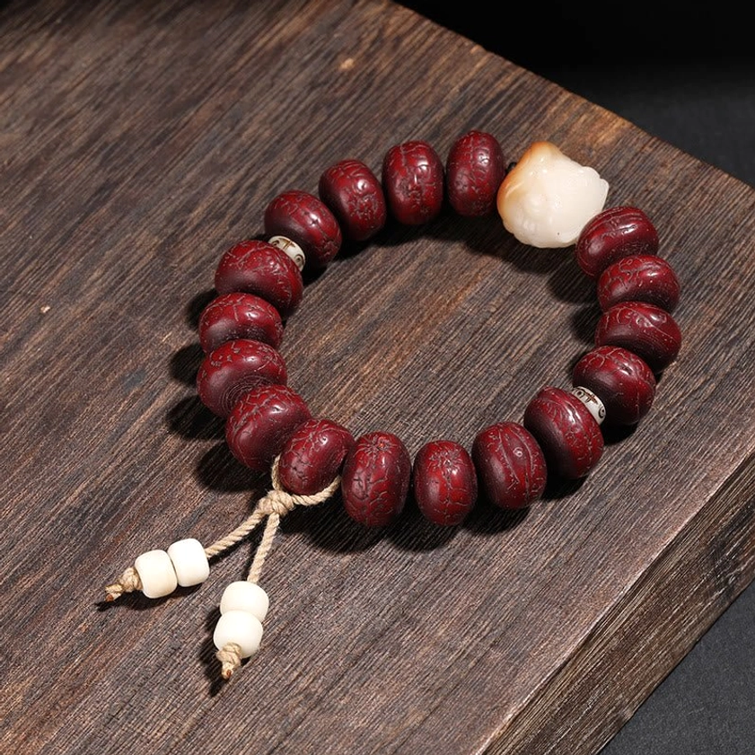 Handmade bodhi seed meditation bracelet with white decorative bead and double tassel pendant on wooden base