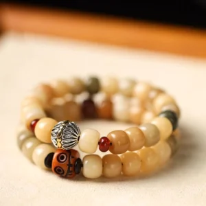 Bodhi seed beaded bracelet with mixed earthy barrel beads and carved silver focal bead, close-up oblique view on wooden tabletop