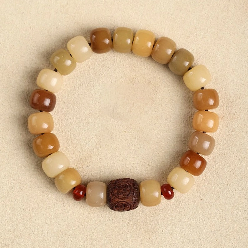 Bodhi seed beaded bracelet overhead flat lay view with earthy gradient colors, wooden carved main bead and tiny red accent beads on beige tabletop