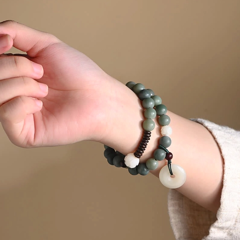 Woman wearing cyan bodhi seed double wrap bracelet on wrist with white sleeve, showing jade peace buckle pendant close-up side view