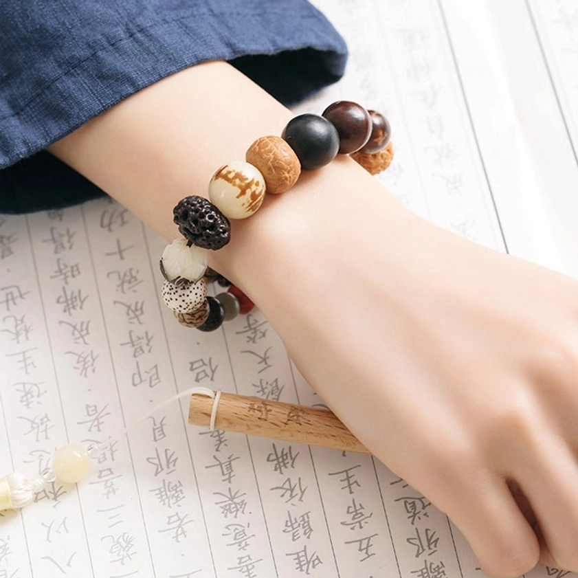 Single bodhi seed mala bracelet on wrist with traditional book background