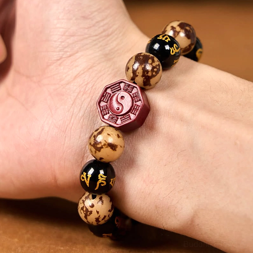 Buddhist Bodhi seed bracelet worn on human wrist showing red cinnabar Bagua charm and natural bead texture in action